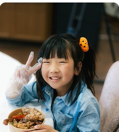 自分でつくった料理を手にして笑う子ども